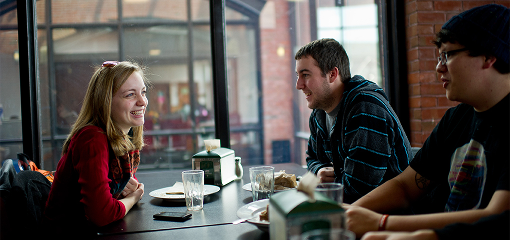 Students laughing and talking in a dining hall
