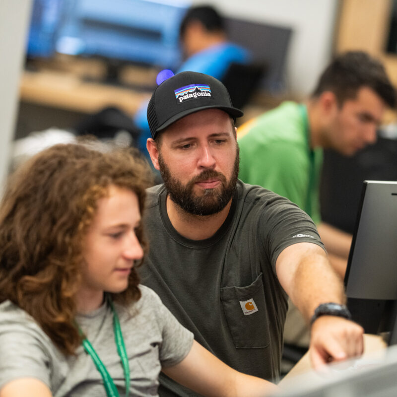 Professor pointing to computer monitor instructing student