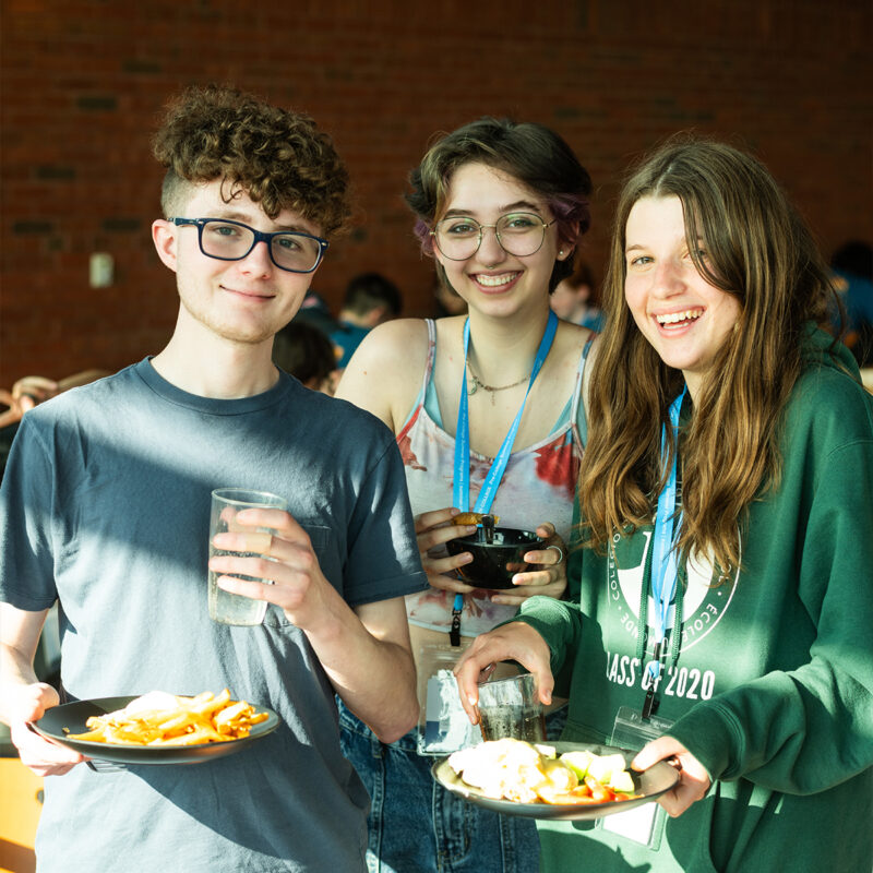 Summer program students holding their meal and smiling at camera