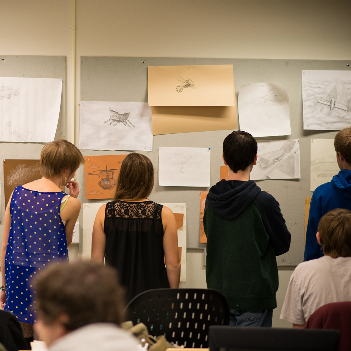 Students looking at art pinned to a wall