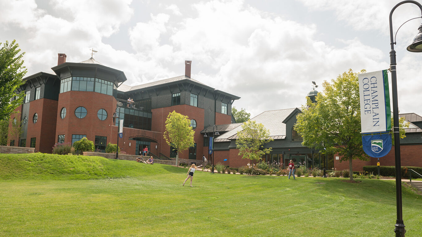 Students playing frisbee on a lawn on Champlain campus