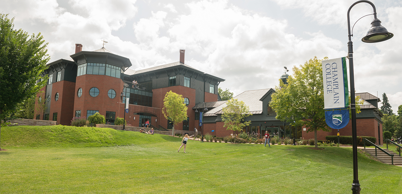 Students playing frisbee on a lawn on Champlain campus