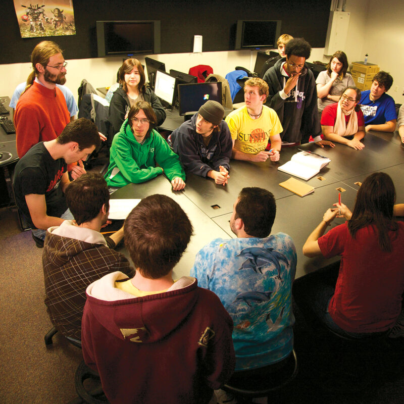 Professor overseeing group of students working at a table