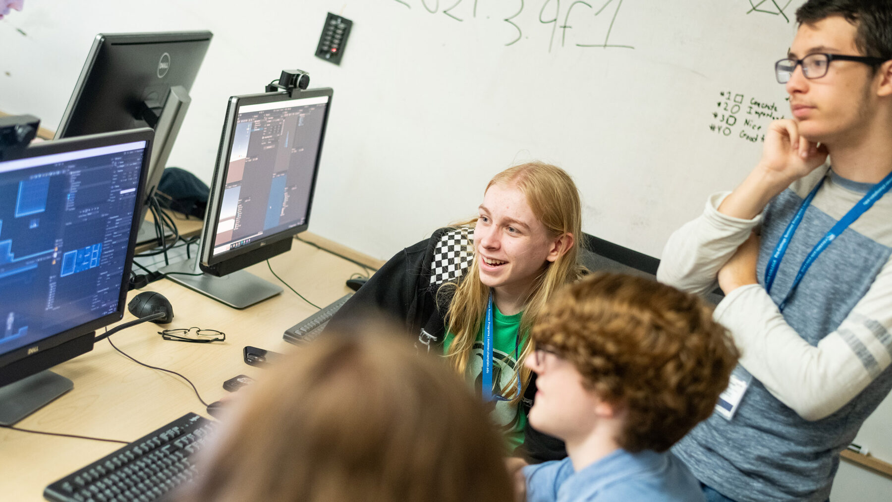 pre-college students gather around a computer to discuss a project